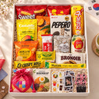 Open Korean snack box packed with biscuits, snack sticks, drinks and coffee, with a pouch and K-pop keepsakes.
