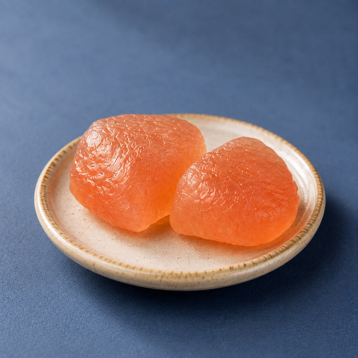 Sakura mochi unwrapped, a soft pale rice cake scented with cherry leaf.